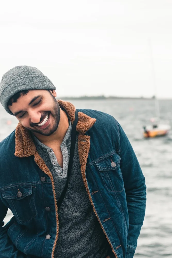 a smiling man wearing a jacket and a hat